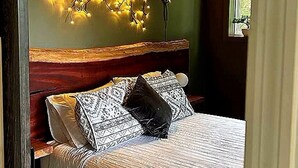 Ett sovrum med en säng, en sänggavel och en väggmonterad lampa.