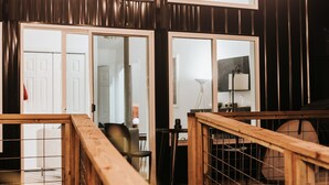 A wooden deck with a railing, a glass door leading to an interior space, and string lights overhead. - Secluded Treehouse Sanctuary with Japanese Ofuro Soaking Tub (Trion)