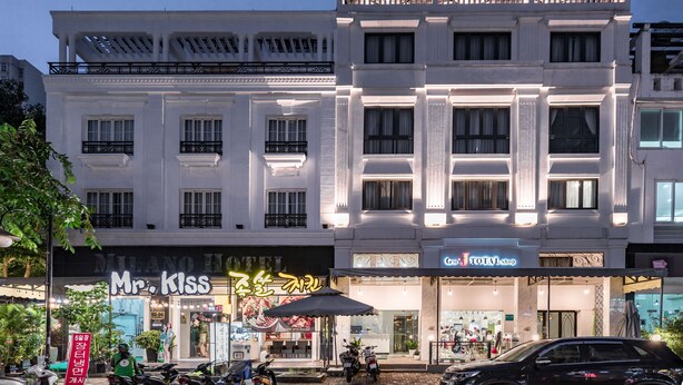 Een meerlaags gebouw met restaurant Mr. Kiss op de begane grond, een Total Shop op de tweede verdieping en een auto ervoor geparkeerd.