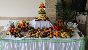 A fruit and vegetable display on a table with a white tablecloth and green accents.