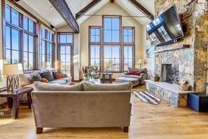 Relax in a spacious living room with a high ceiling, comfortable seating area, and a fireplace.