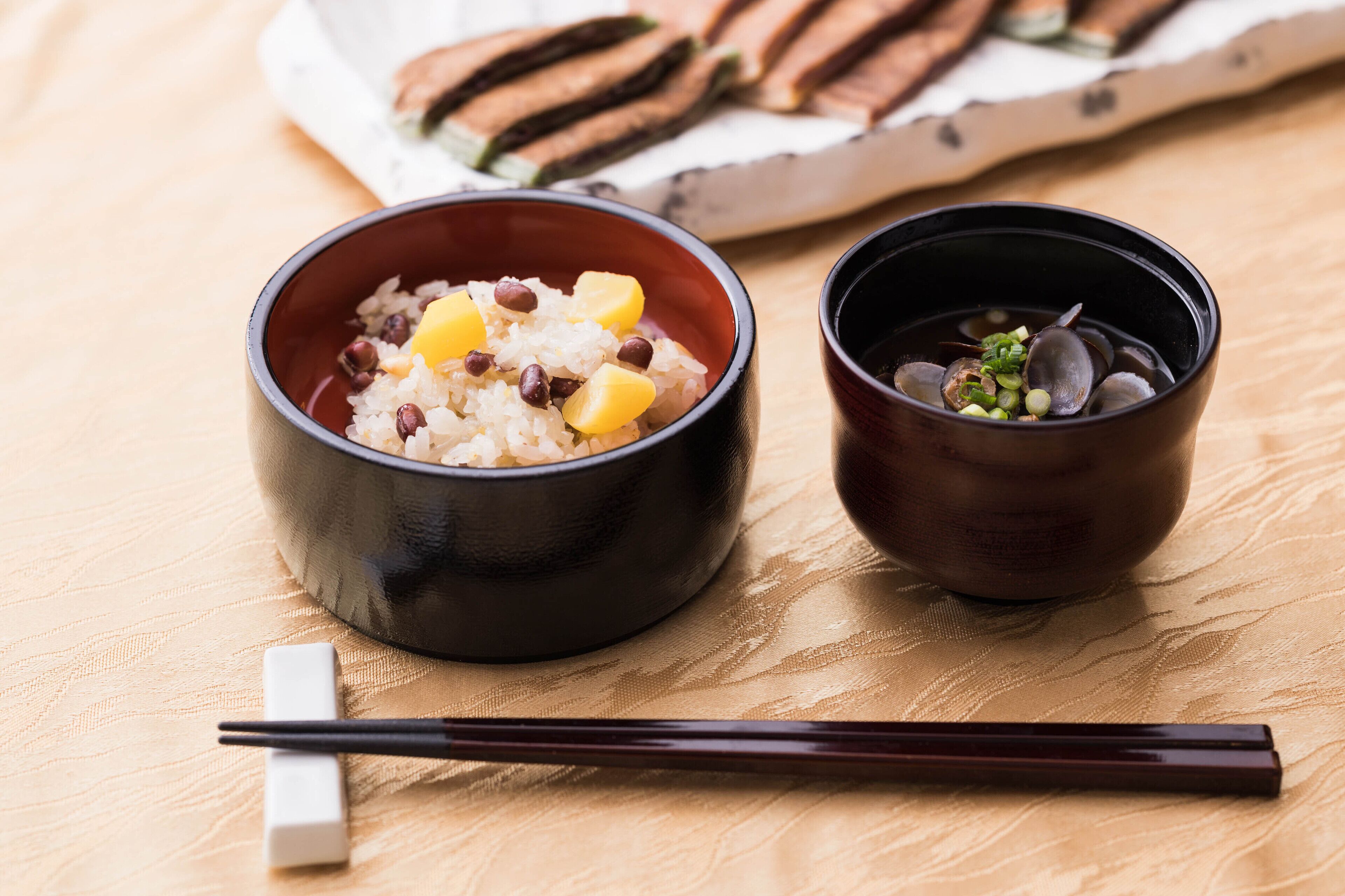 Two bowls of food on a table with chopsticks and a napkin.