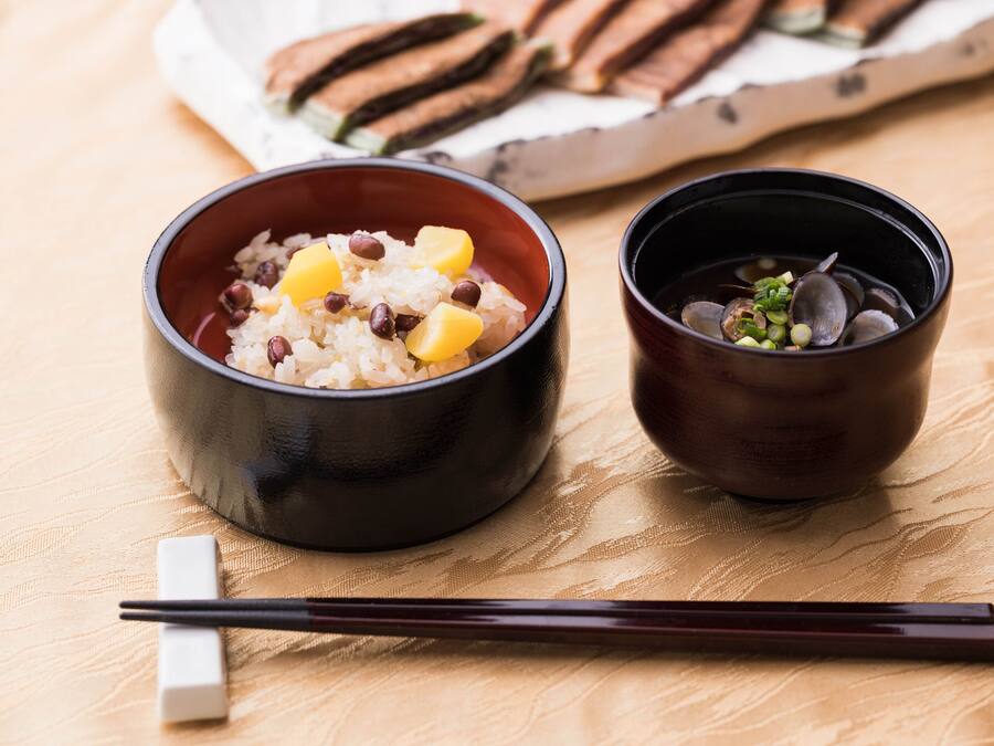 Two bowls of food on a table with chopsticks and a napkin.
