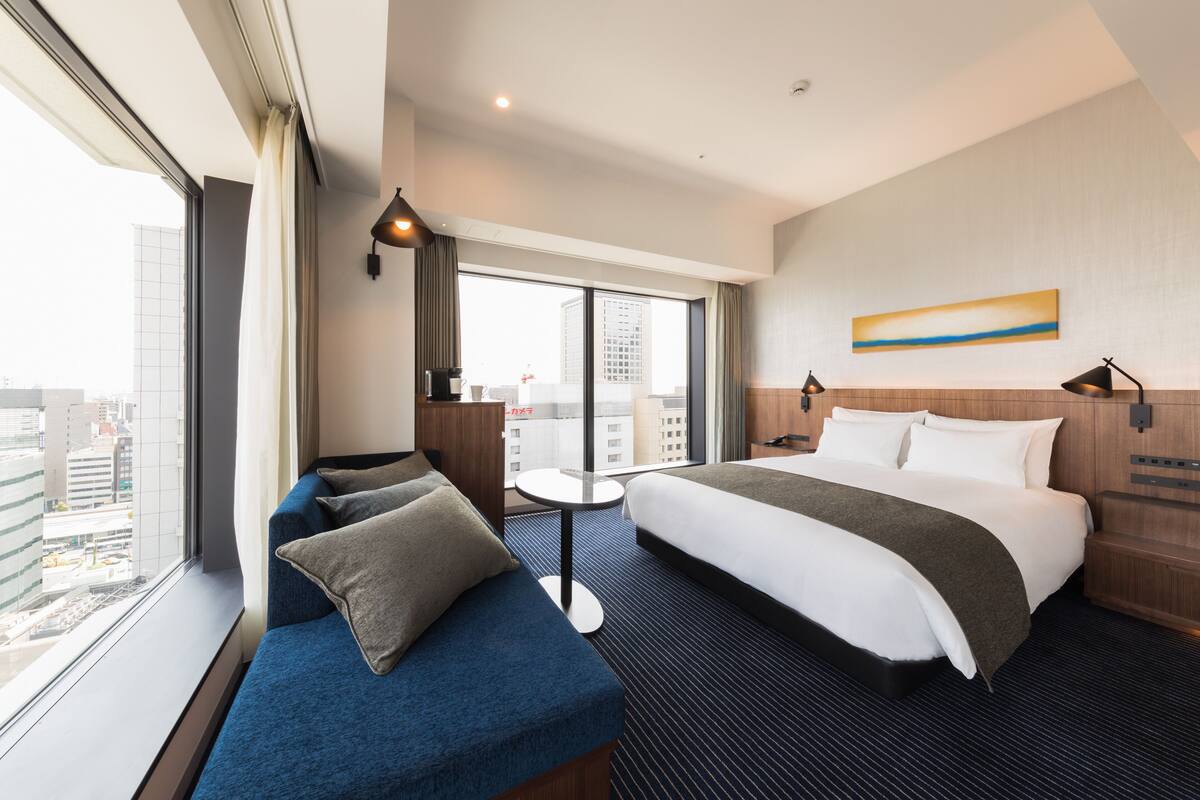Hotelkamer met een groot bed, een sofa, een tafeltje en uitzicht op de stad.
