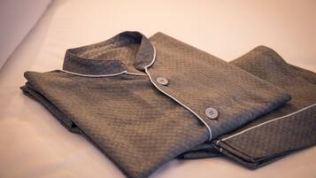 A neatly folded shirt with a button and a collar, placed on a bed.