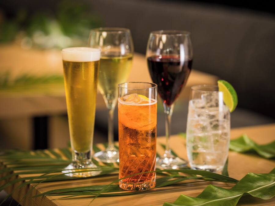A variety of drinks on a wooden table with green leaves.