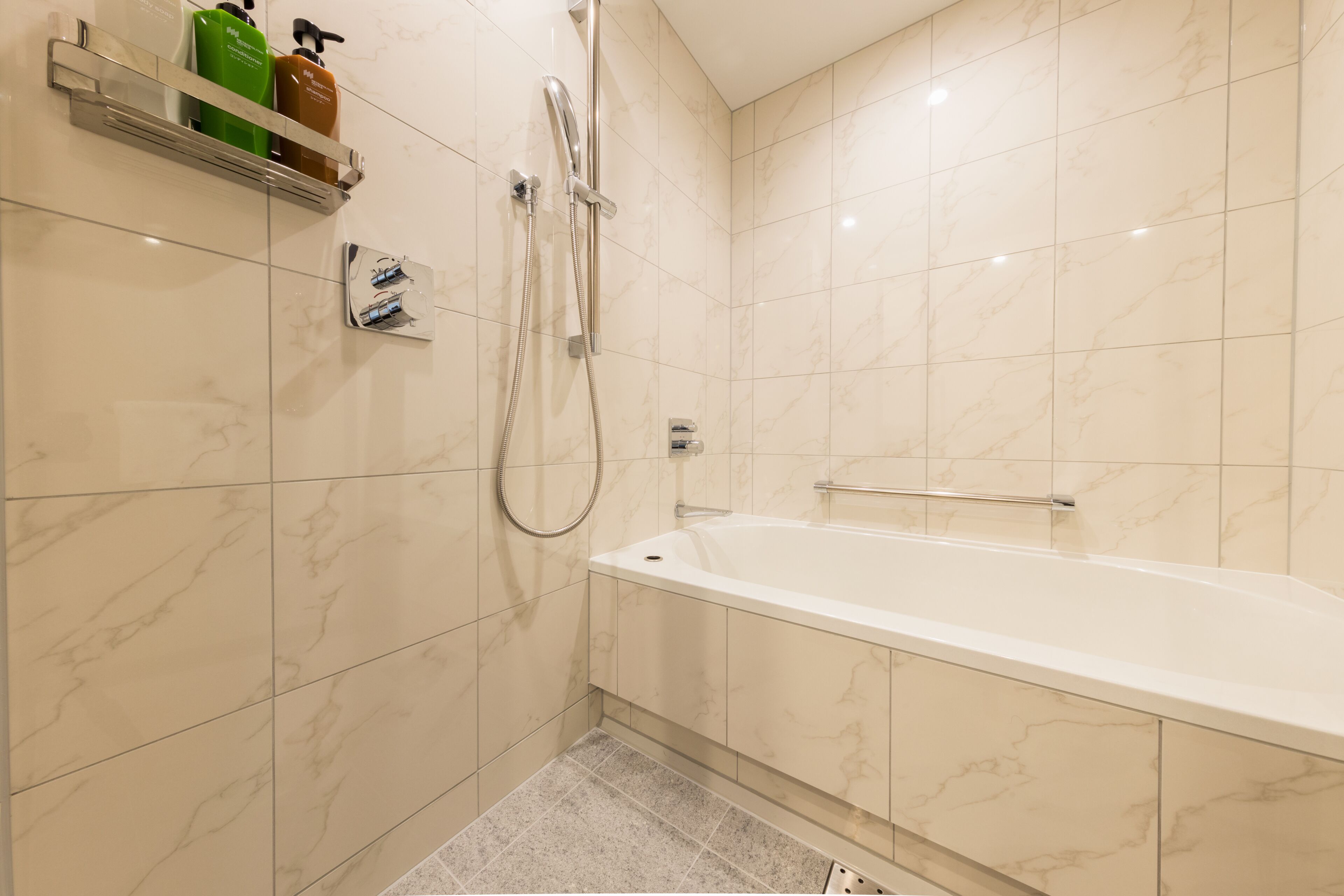 Een moderne badkamer met een bad, douche en handdroger.