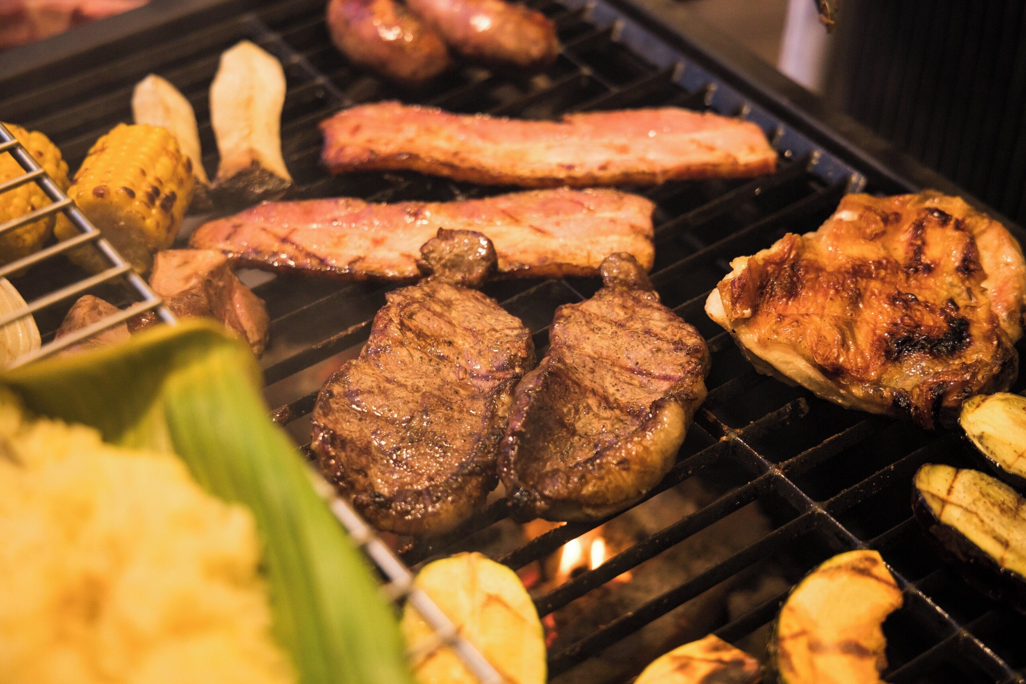 A grill with various meats and vegetables being cooked.