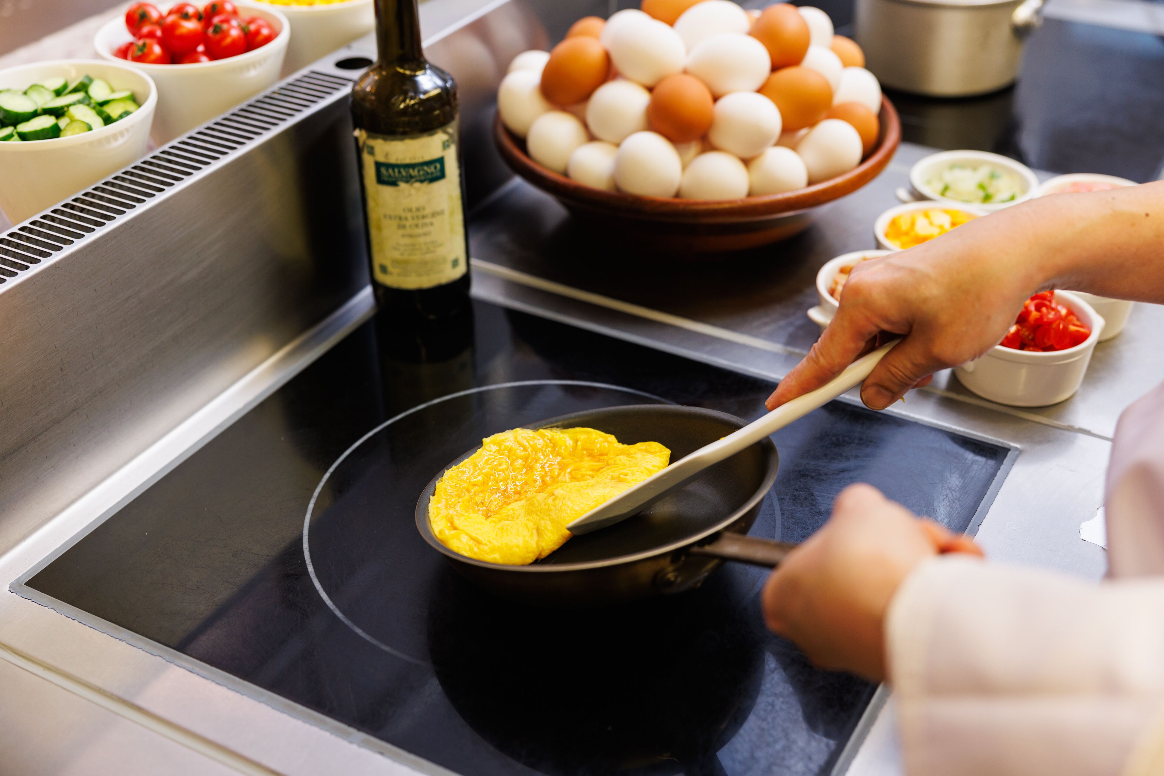 Una cucina con un fornello, una ciotola di uova e diversi ingredienti.