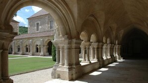 A courtyard with a series of arches and columns, leading to a building with a tiled roof. - Chambres sous les vignes du Buttois (Bussy-le-Grand)