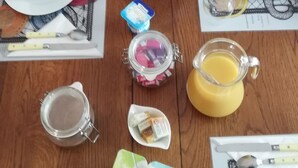 A wooden dining table set with breakfast items including bread, eggs, and juice. - Chambres sous les vignes du Buttois (Bussy-le-Grand)