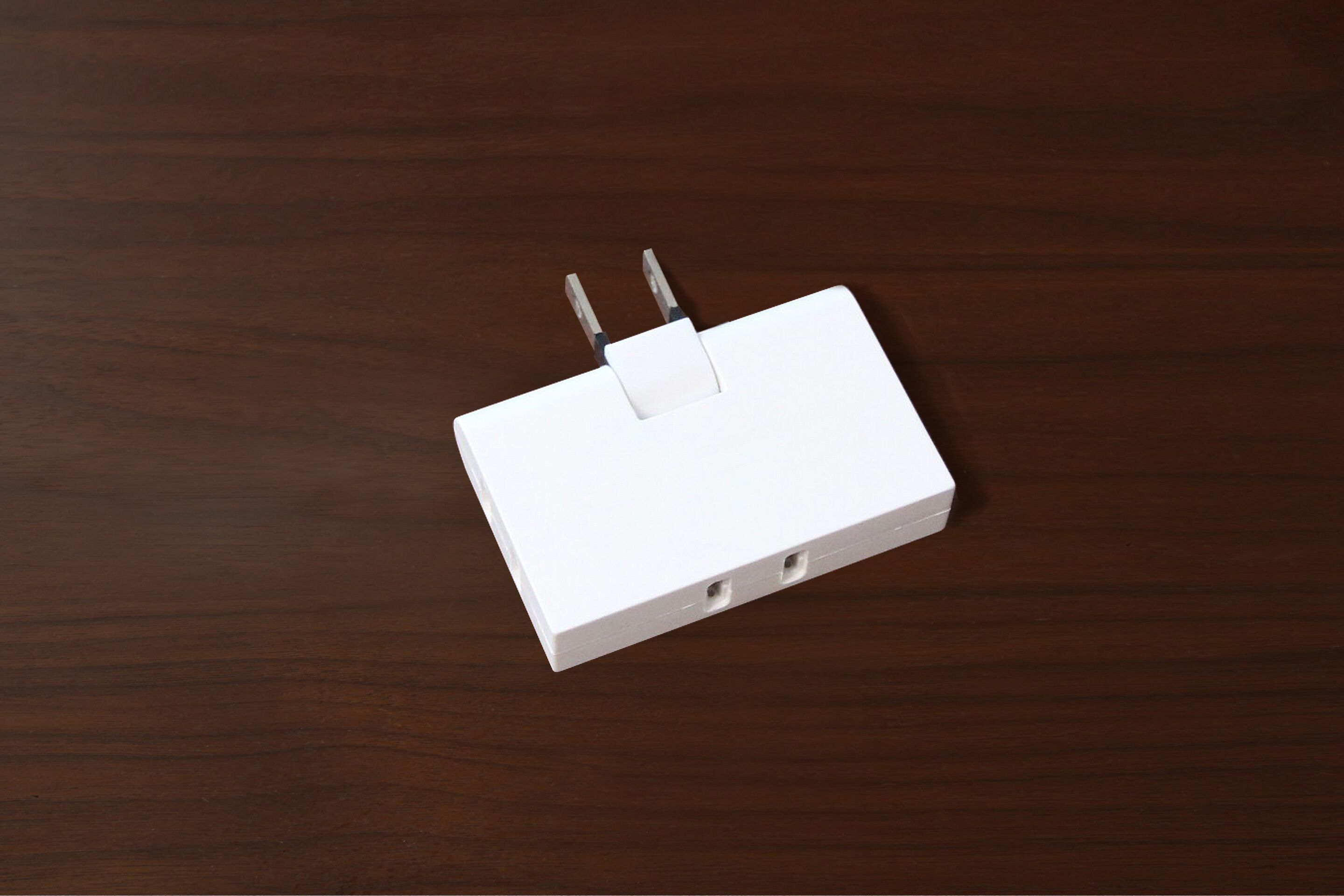 A white power strip with two plugs on a wooden surface.