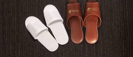 A pair of white and brown slippers with a logo on the brown ones.