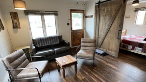 Ein gemütliches Wohnzimmer mit einer Couch, Sesseln, einem Couchtisch und einem Deckenventilator.