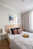 Un dormitorio ordenado con una cama grande, una mesita de noche con un reloj y una bandeja con alimentos para el desayuno.
