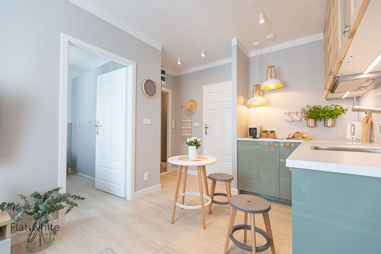 Una cucina moderna con isola centrale, sgabelli e illuminazione a sospensione.