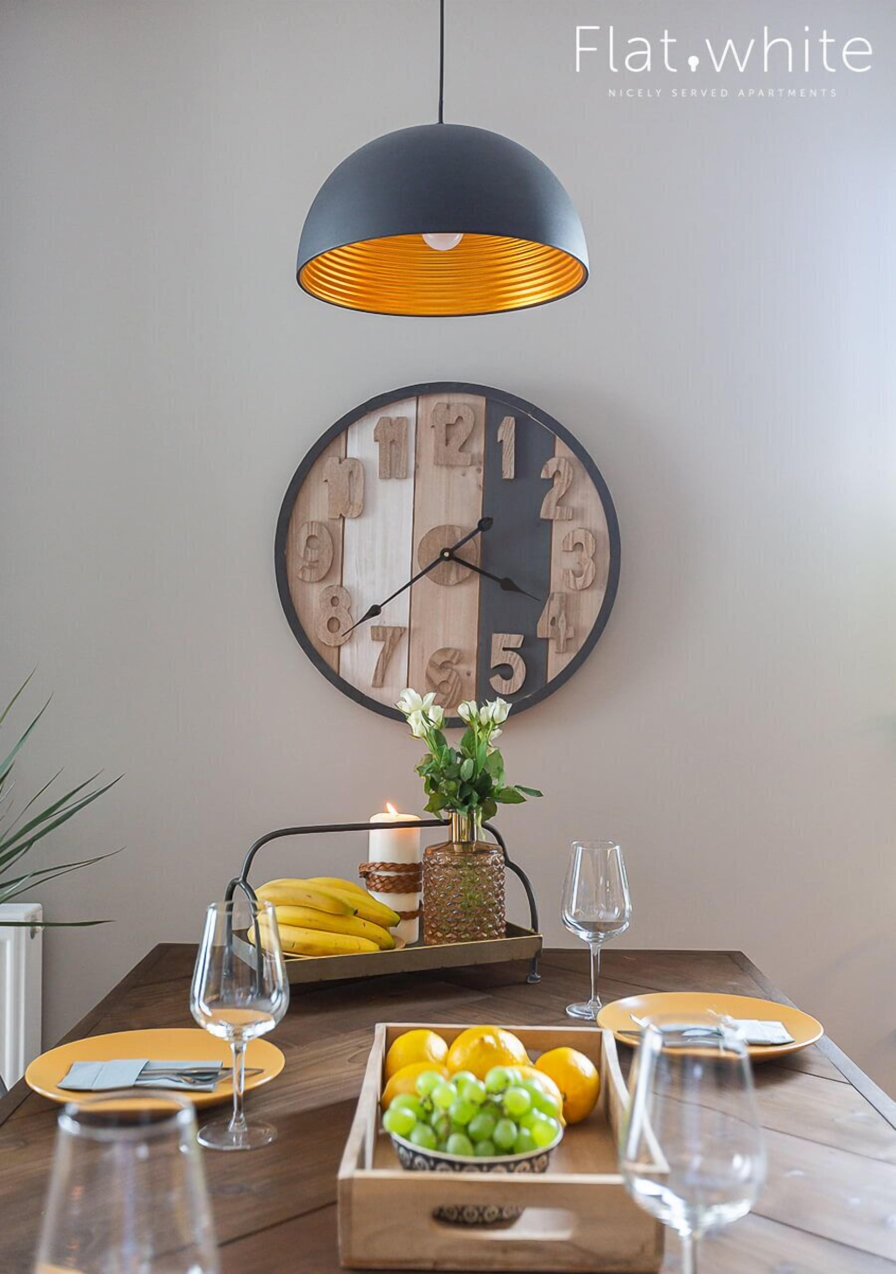 Un coin repas avec une table en bois, une horloge et une suspension.