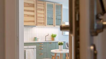 Une cuisine moderne avec des meubles en bois, un plan de travail blanc et une table ronde accompagnée de tabourets.