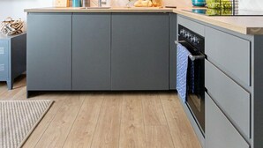 A modern kitchen with dark cabinets, a wooden countertop, and a built-in oven. - Flat White Apartamenty Obywatelska 47 (Zielona Gora)