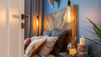 A bedroom with a wooden headboard, a bedside table with a candle, and a wall-mounted light fixture.