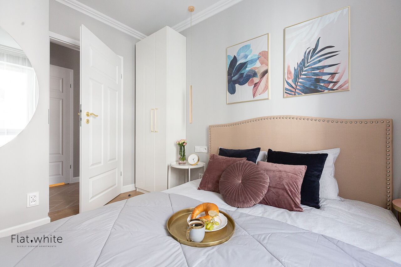 A neatly arranged bedroom with a bed, bedside table, and a tray with breakfast items.