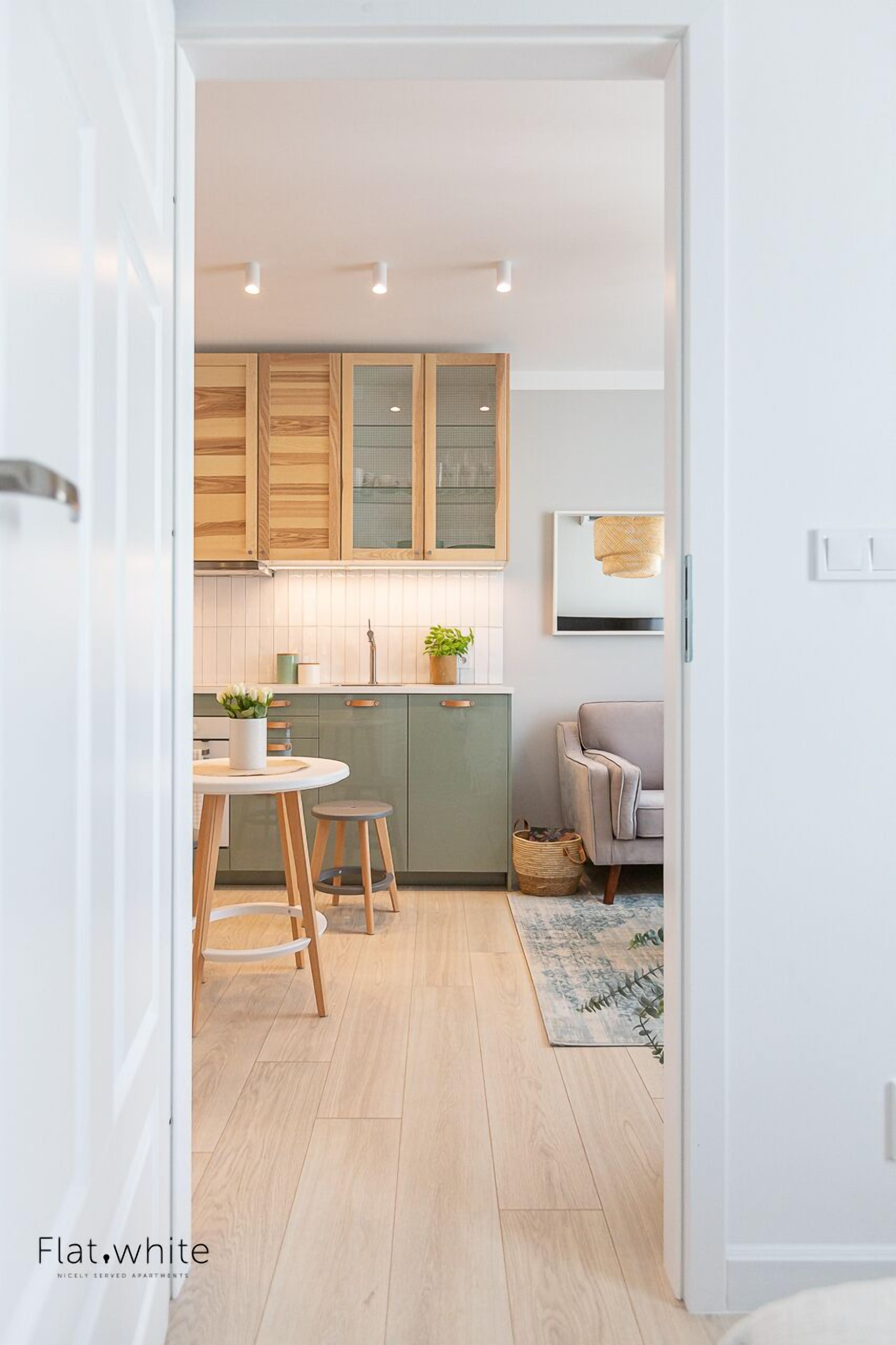 Une cuisine moderne avec des meubles de rangement en bois, une table de salle à manger ronde et un petit tabouret.