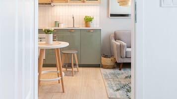 Une cuisine moderne avec des meubles de rangement en bois, une table de salle à manger ronde et un petit tabouret.
