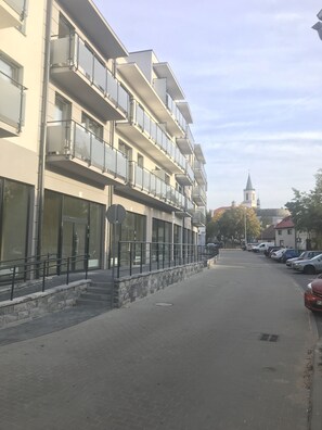 Un edificio de varios pisos con balcones, ventanas amplias y una iglesia al fondo.