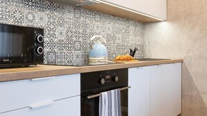 Une cuisine avec un crédence décorée, un four à micro-ondes, une bouilloire et un grille-pain.