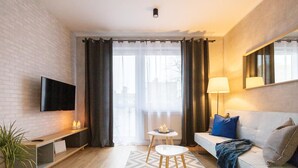 Un salon moderne avec un téléviseur à écran plat, un canapé, une table basse et une lampe.