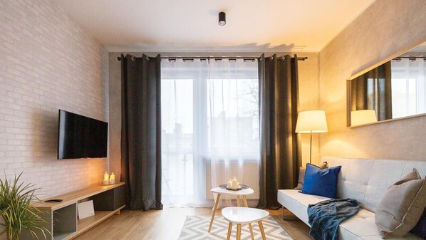 Uma sala de estar moderna com televisão de tela plana, um sofá, uma mesa de centro e um abajur.