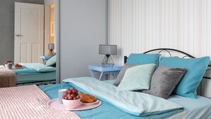 Une chambre à coucher avec un lit, des tables de chevet, une lampe et un panier de fruits.
