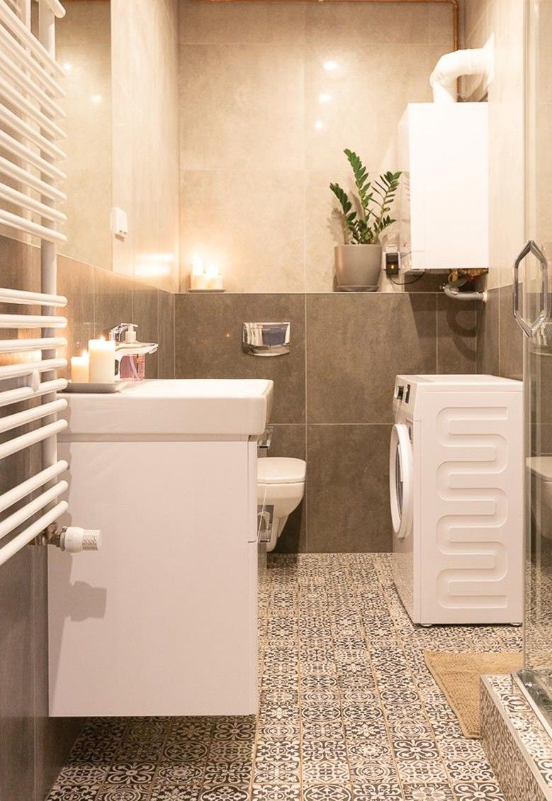 A compact bathroom with a toilet, washing machine, and a radiator.