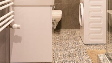 A compact bathroom with a toilet, washing machine, and a radiator.
