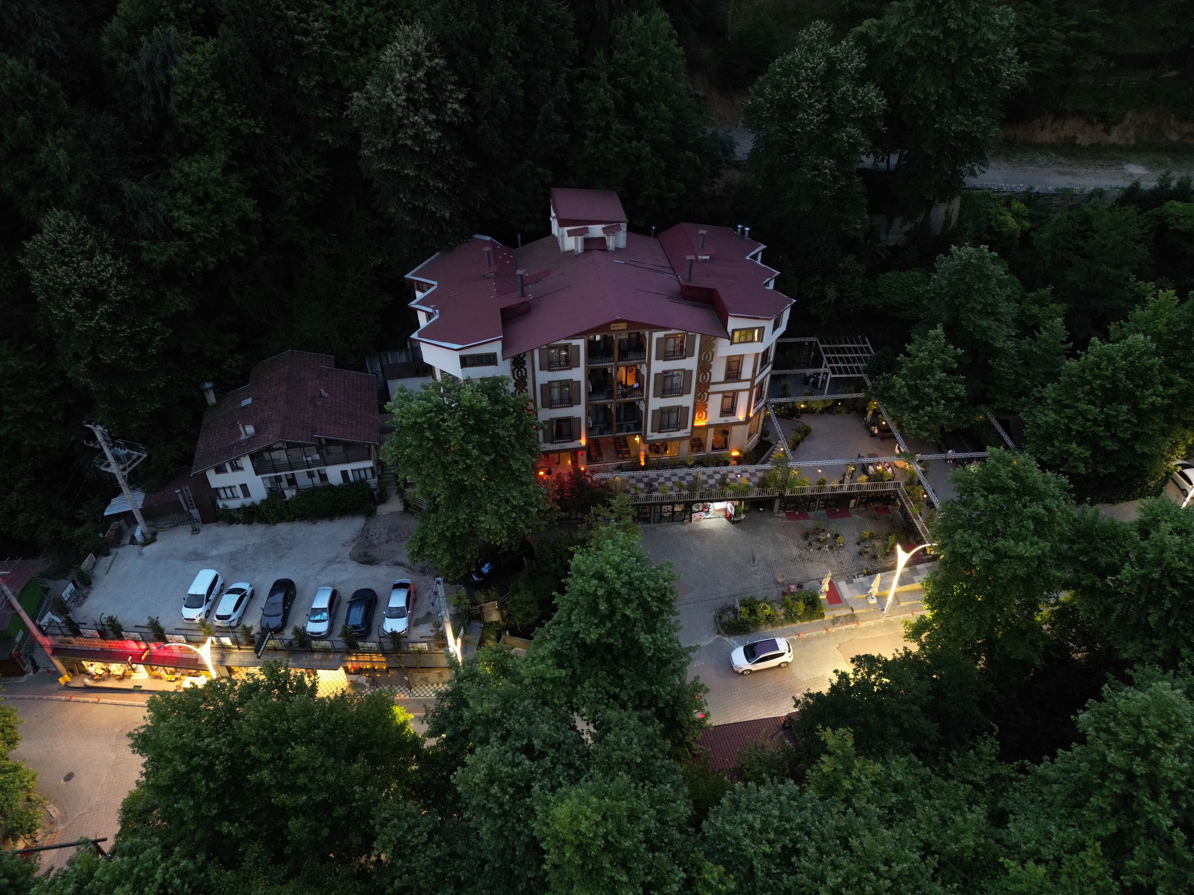 Une vue aérienne d’un hôtel à plusieurs étages, doté d’un toit rouge et entouré d’une végétation luxuriante.