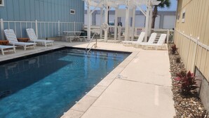 Una piscina con sillas de descanso y una pérgola.