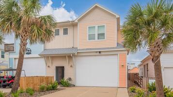 A two-story house with a garage, a driveway, and a wooden fence.