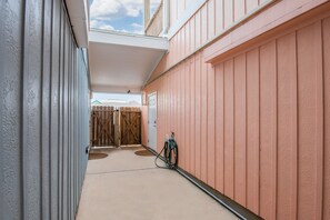 A narrow hallway with a covered area, a wooden gate, and a hose on the right. - Hot tub, Pool, blackouts, 75" TV, Dogs OK (Port Aransas)