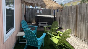 Un patio trasero con cerca de madera, una parrilla y dos sillas Adirondack.