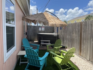 A backyard with a wooden fence, a barbecue grill, and two Adirondack chairs.