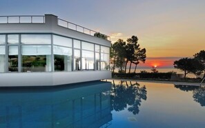 A modern building with large windows and a pool reflecting the sunset. - Krotiri Resort (Sithonia)