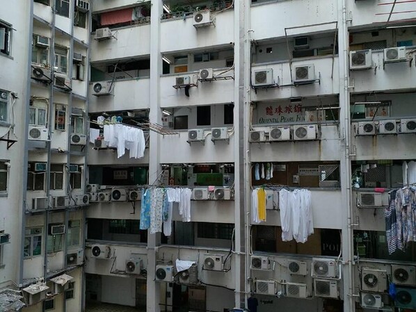 A multi-story building with balconies, air conditioning units, and laundry hanging on lines. - Hop Inn On Nathan Road (Kowloon)