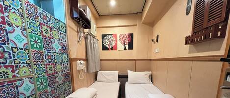 A room with two beds, a telephone, and a wall with colorful tiles.