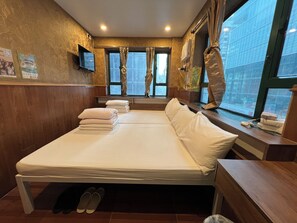 A hotel room with a large bed, a TV mounted on the wall, and a window with curtains. - Hop Inn On Nathan Road (Kowloon)