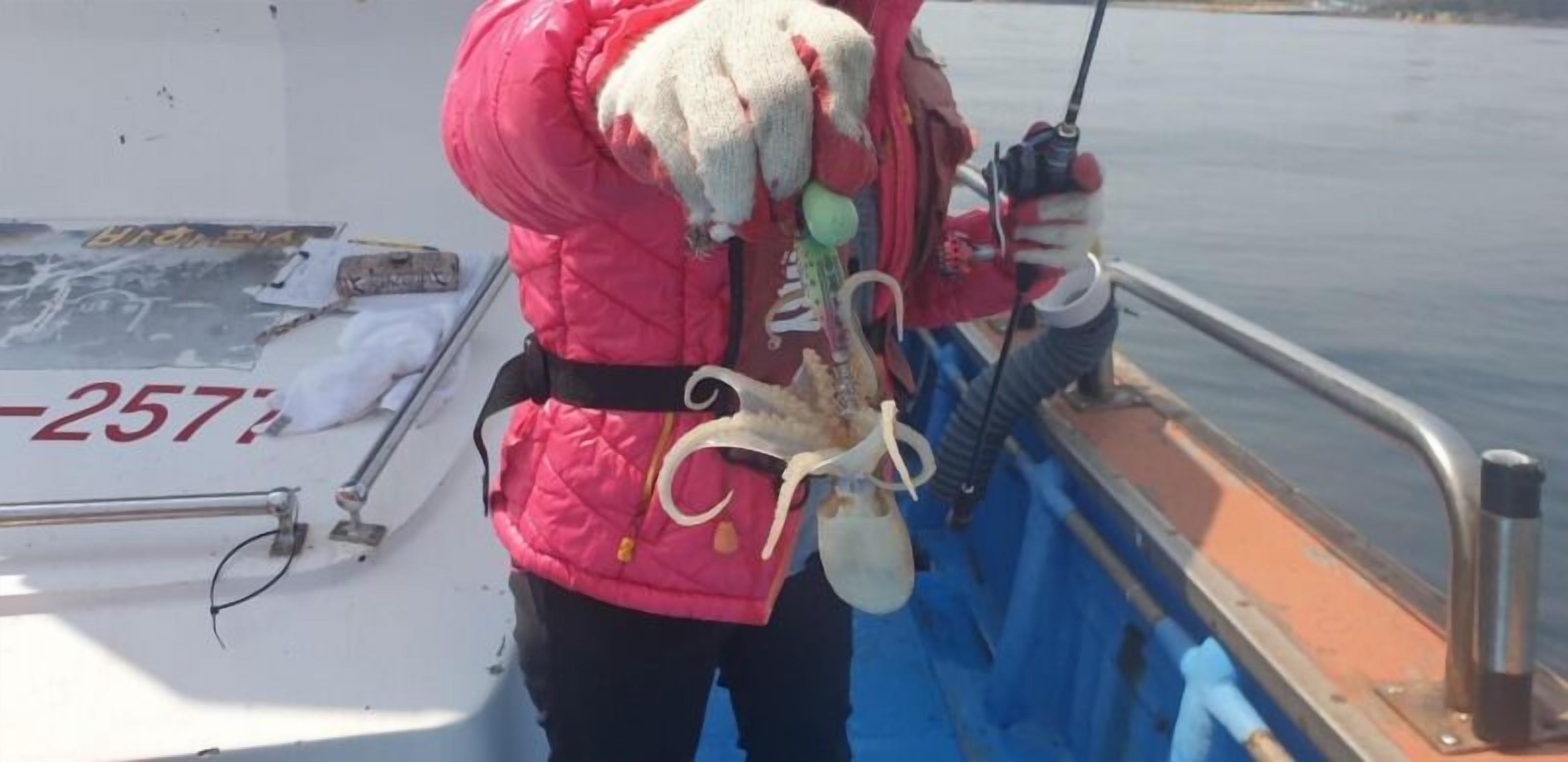 A person on a boat holding a large octopus.