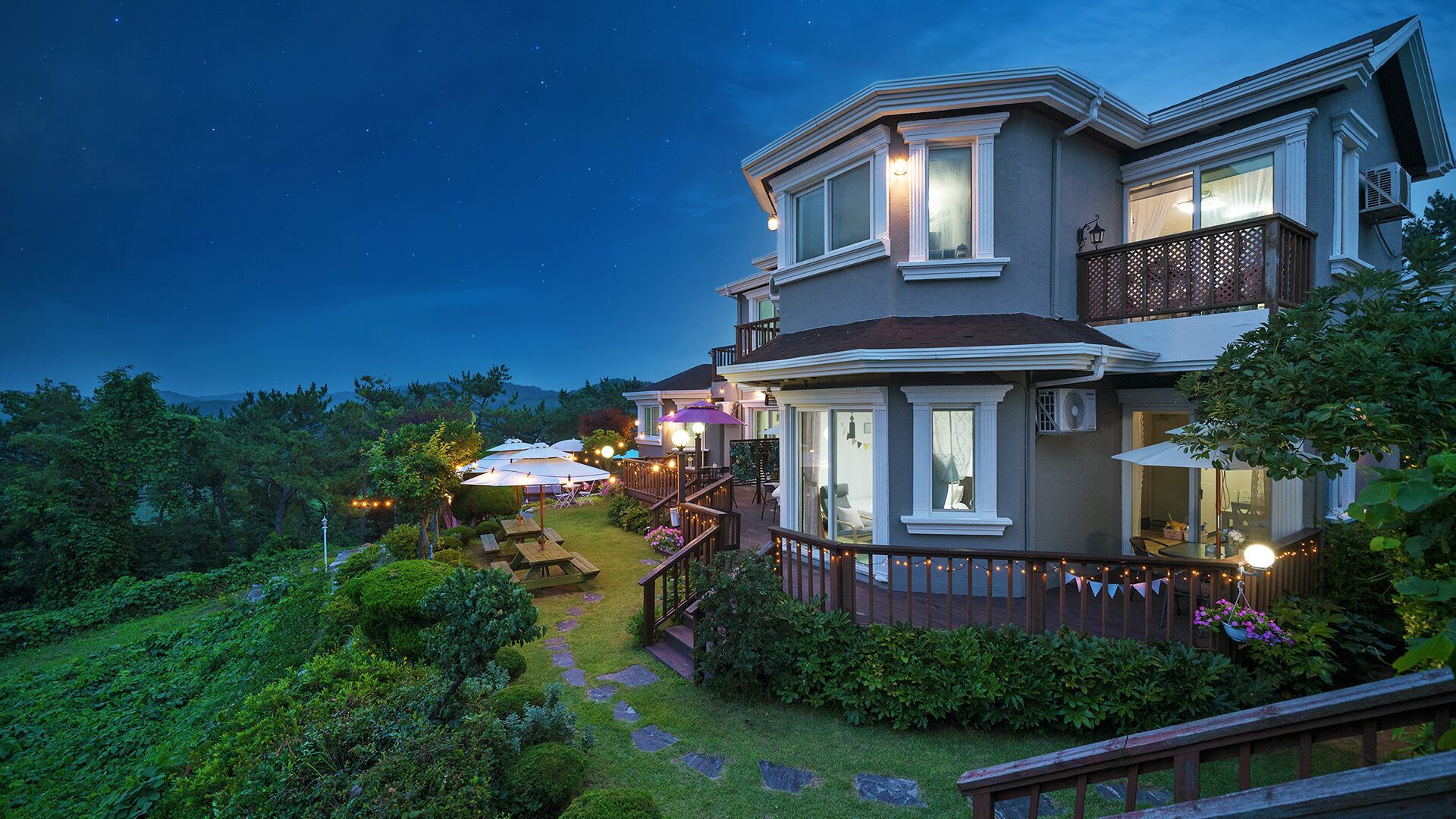A two-story house with a balcony, a deck, and a garden.