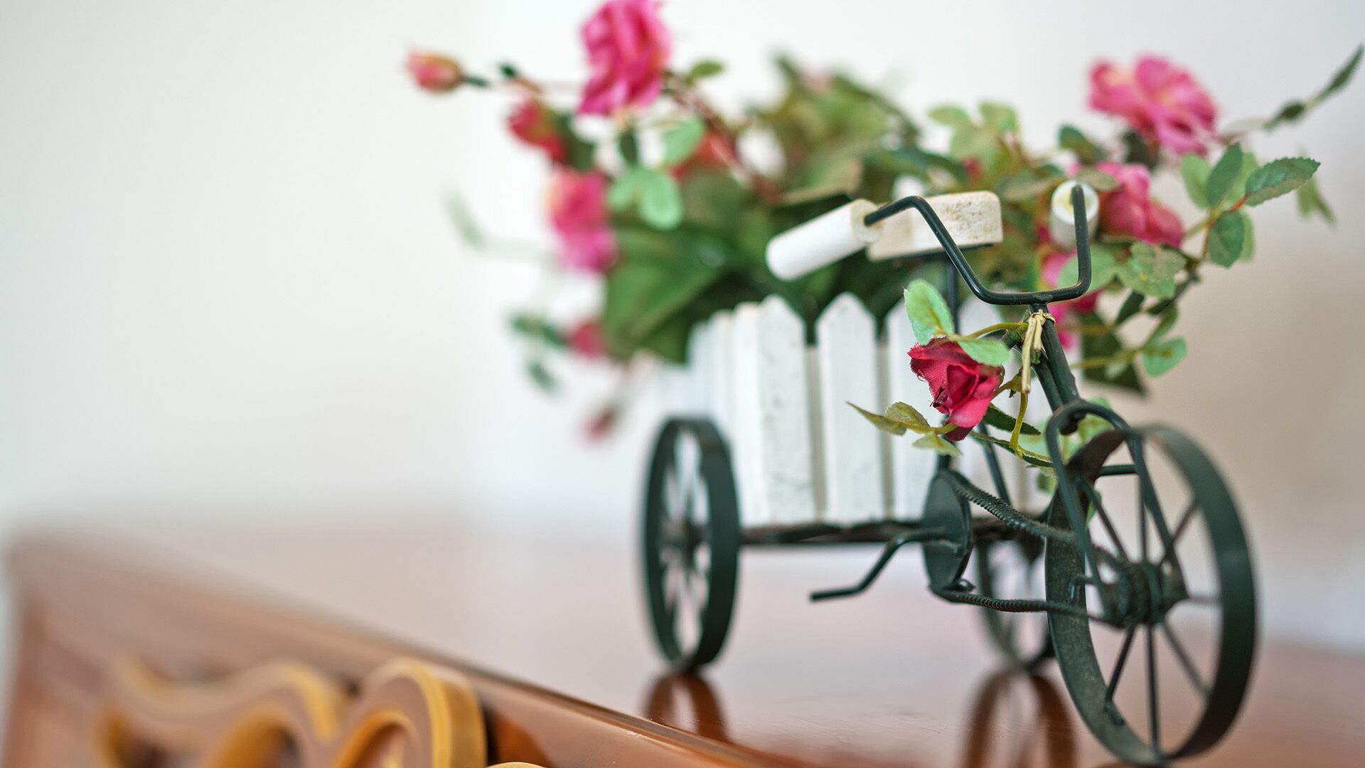 A small bicycle planter with pink flowers.
