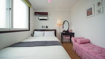 Et pænt indrettet hotelværelse med seng, skrivebord med stol, et sminkebord med spejl og en lyserød sofa.