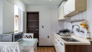 A compact kitchen with a microwave, a glass-top table, and a sink.