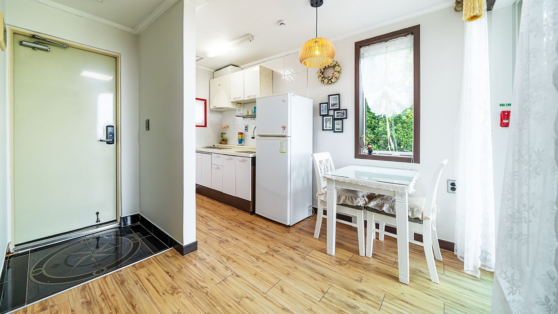 Een moderne keuken met witte kasten, een koelkast en een eethoek met een witte tafel en stoelen.